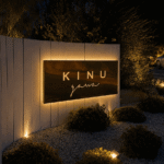 Kinugawa Ramatuelle restaurant entrance at night with an illuminated sign, white fence, landscaped garden, and warm ambient lighting in Saint-Tropez, France.