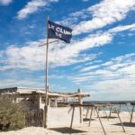 Le Club 55 flag and beach setup by the shore, Saint-Tropez
