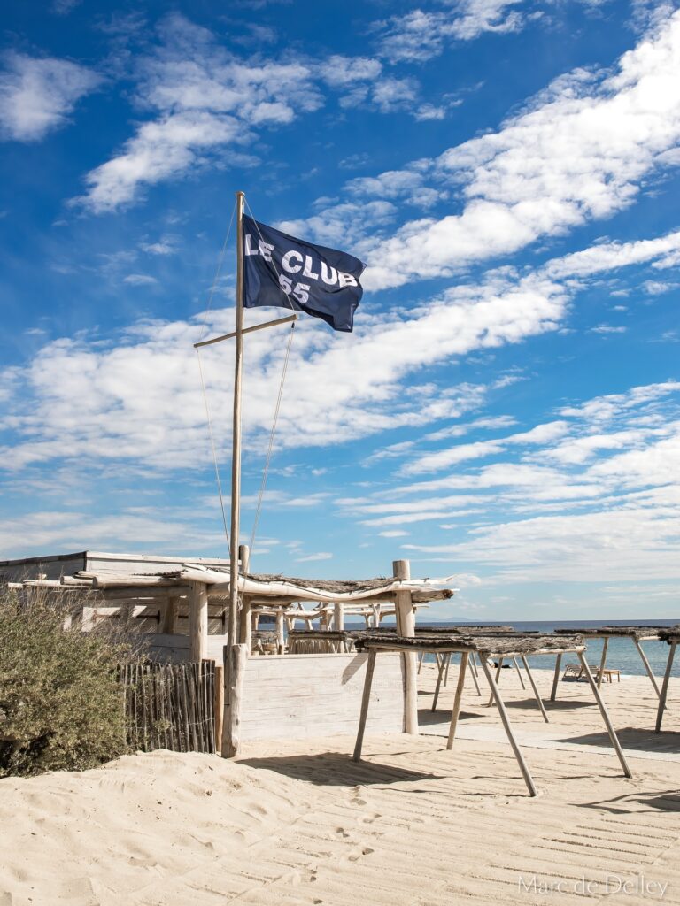 Le Club 55 flag and beach setup by the shore, Saint-Tropez