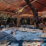 Tables set with signature blue checkered linen under the reed-roof terrace at Le Club 55, Saint-Tropez