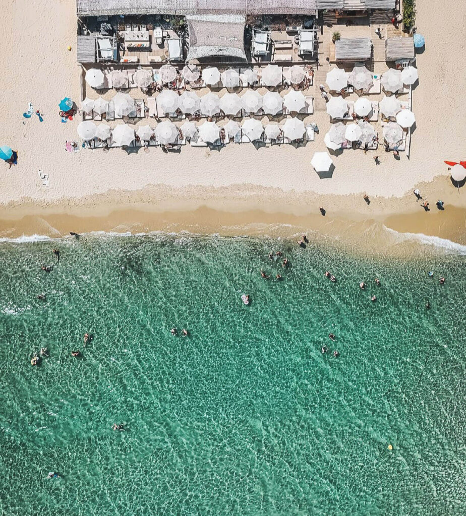 Aerial view of Verde Beach with rows of white parasols along the sand and turquoise water