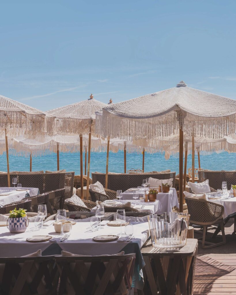 Verde Beach restaurant tables dressed in white linen under fringed parasols facing the sea