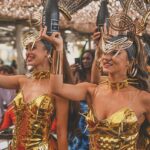 Costumed performers carrying champagne bottles during a parade at Verde Beach