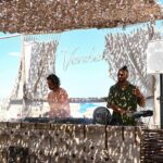 DJs performing at the Verde Beach booth beneath the illuminated Verde sign