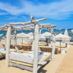 Driftwood daybed on the sand at Verde Beach facing the sea and parasol rows