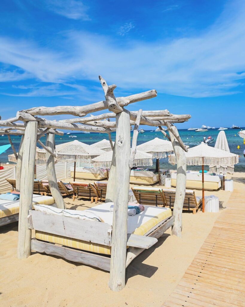 Driftwood daybed on the sand at Verde Beach facing the sea and parasol rows