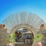 Arched reed entrance leading into Verde Beach club from the sand