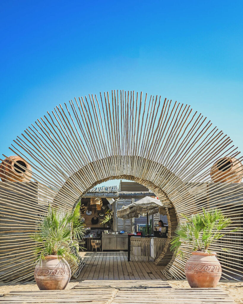 Arched reed entrance leading into Verde Beach club from the sand