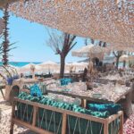 Shaded lounge sofa with teal cushions at Verde Beach, looking out over parasols and the sea