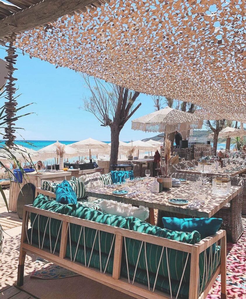 Shaded lounge sofa with teal cushions at Verde Beach, looking out over parasols and the sea