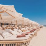Rows of cushioned sunbeds under fringed parasols on the sand at Verde Beach