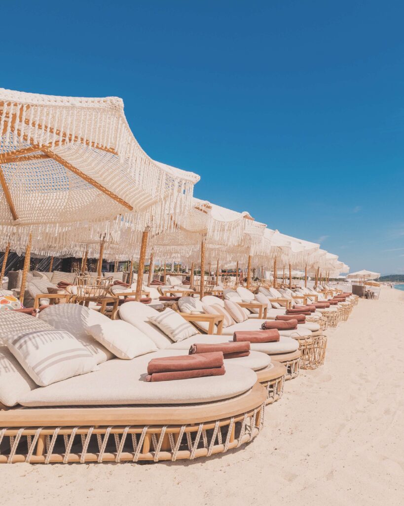Rows of cushioned sunbeds under fringed parasols on the sand at Verde Beach