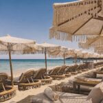 Verde Beach sunbeds and fringed parasols lined along the shore with a clear sea view