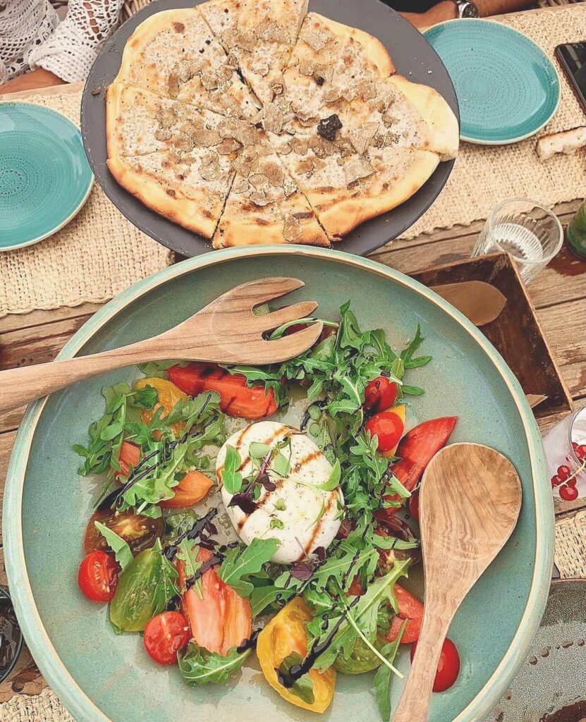Truffle pizza and burrata salad with heirloom tomatoes and rocket served at Verde Beach