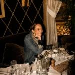 Guest seated at a candlelit banquette by a studded diamond-tufted wall at L'Avenue Paris