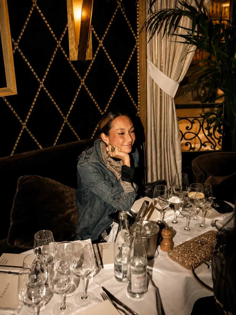 Guest seated at a candlelit banquette by a studded diamond-tufted wall at L'Avenue Paris