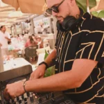DJ mixing under a parasol during a daytime set at Byblos Beach Ramatuelle