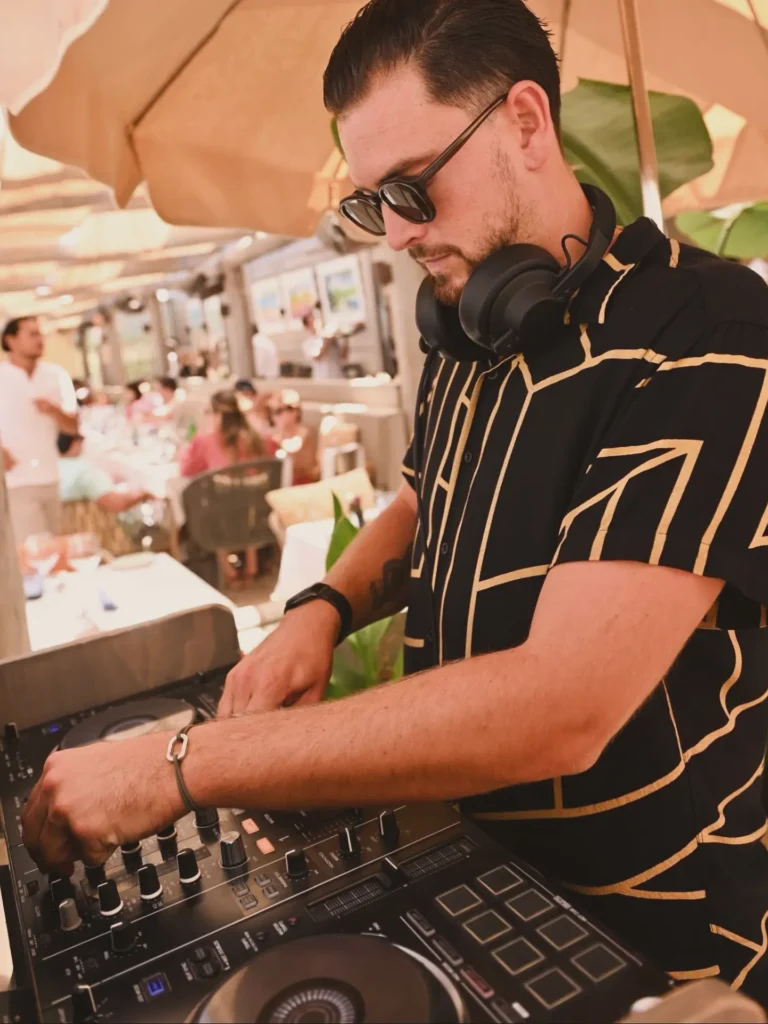 DJ mixing under a parasol during a daytime set at Byblos Beach Ramatuelle