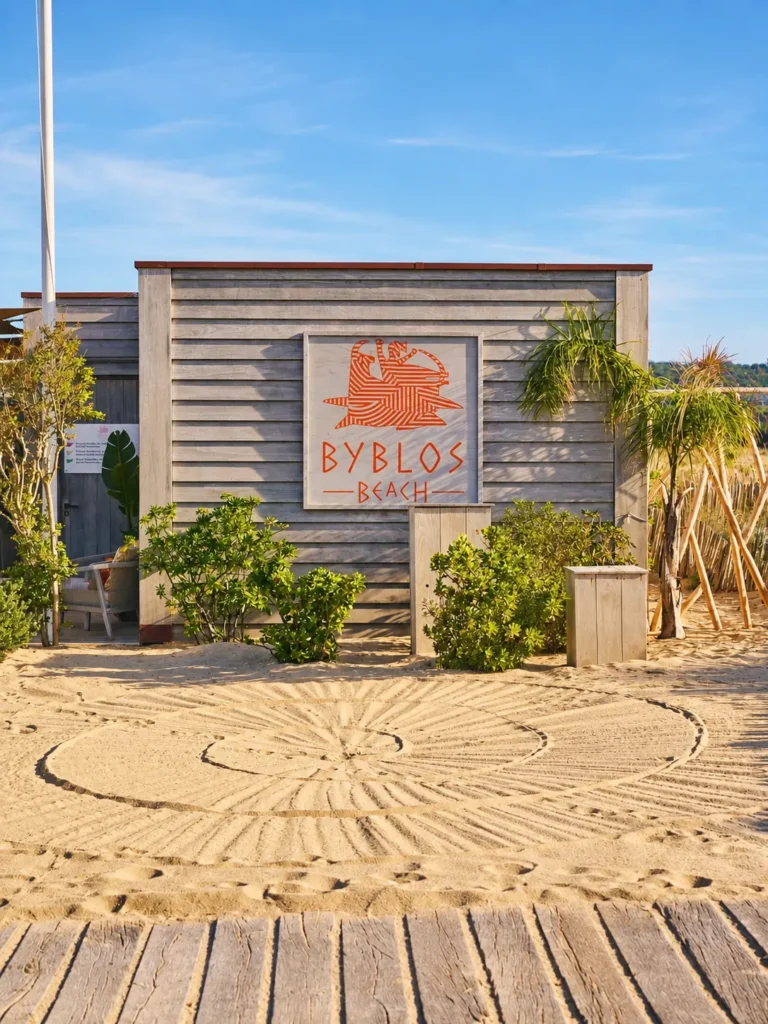 Byblos Beach signage on a weathered wooden beach hut with raked sand at Byblos Beach Ramatuelle