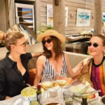 Three guests chatting over lunch and wine at Byblos Beach Ramatuelle