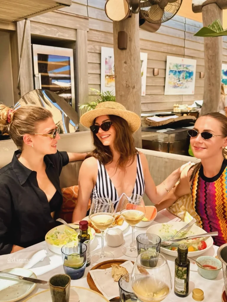 Three guests chatting over lunch and wine at Byblos Beach Ramatuelle