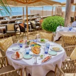 Beachside table laid with a shared lunch spread and sea view at Byblos Beach Ramatuelle