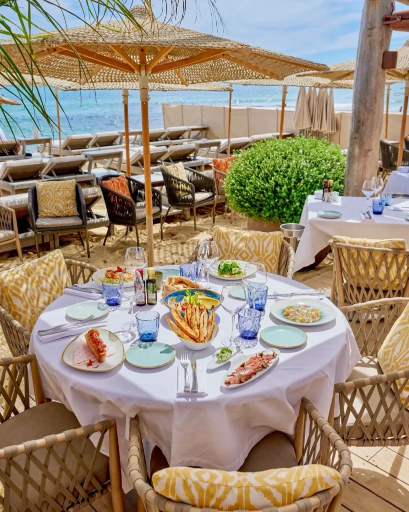 Beachside table laid with a shared lunch spread and sea view at Byblos Beach Ramatuelle