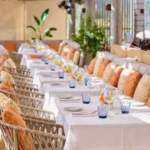 Long banquette lined with orange and yellow cushions beside set tables at Byblos Beach Ramatuelle
