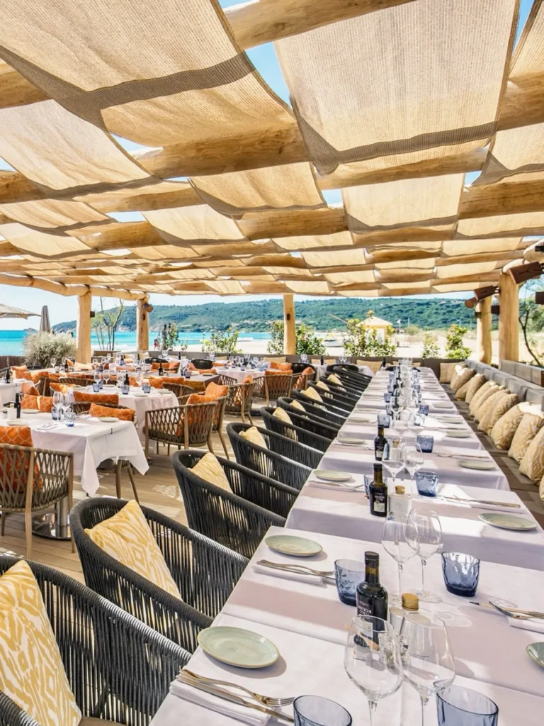 Long dining table and banquette seating under a canopy at Byblos Beach Ramatuelle