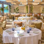 Round table set with linens and glassware in the beach restaurant at Byblos Beach Ramatuelle