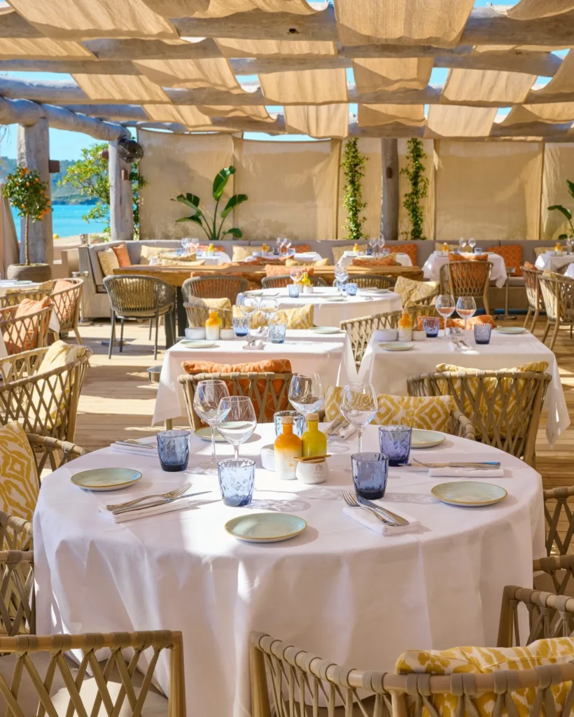 Round table set with linens and glassware in the beach restaurant at Byblos Beach Ramatuelle