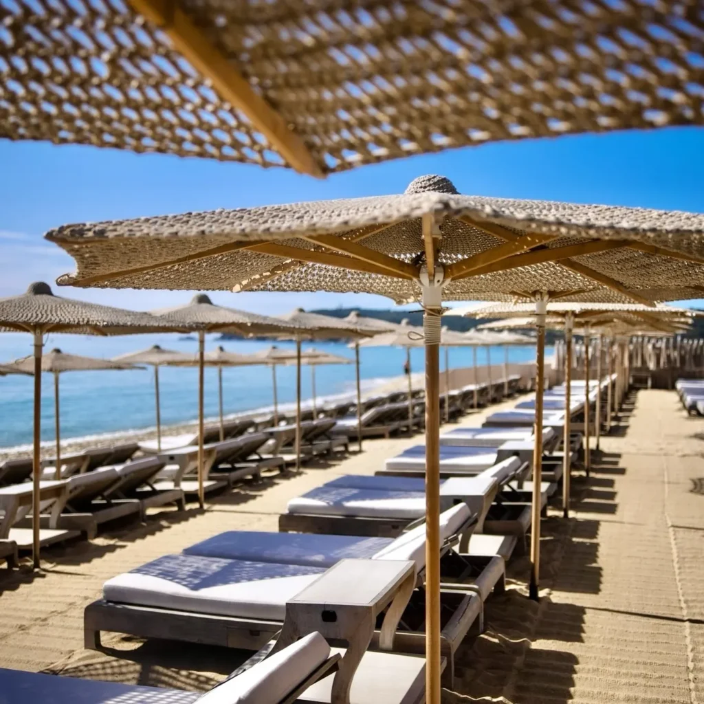 White sunbeds beneath woven straw umbrellas on the sand at Byblos Beach Ramatuelle