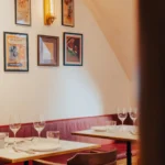 Corner banquette and marble tables below framed bullfighting posters at El Caminito Palma