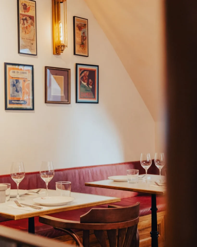 Corner banquette and marble tables below framed bullfighting posters at El Caminito Palma