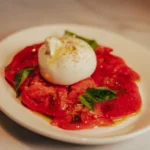 Burrata over sliced tomato carpaccio with basil and olive oil at El Caminito Palma
