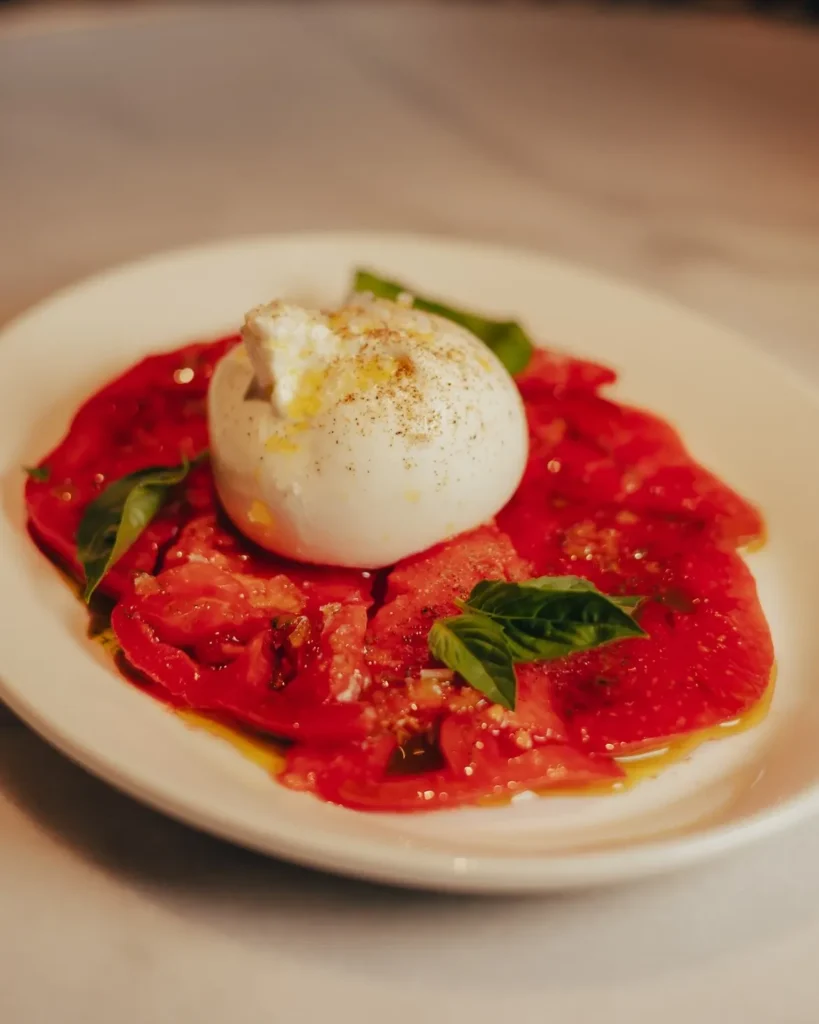 Burrata over sliced tomato carpaccio with basil and olive oil at El Caminito Palma