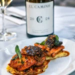 Glazed chicken topped with morels beside a bottle of house El Camino wine at El Caminito Palma