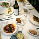 Overhead spread of octopus, croquettes, almonds and house wine on a marble table at El Caminito Palma