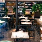 Dining room with bistro tables in front of a floor-to-ceiling wine wall at El Caminito Palma