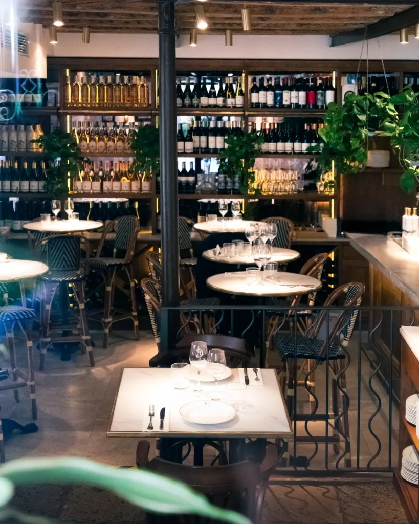 Dining room with bistro tables in front of a floor-to-ceiling wine wall at El Caminito Palma