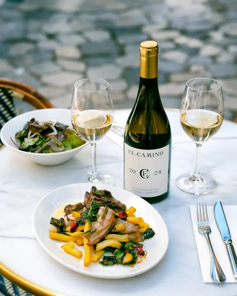 Lamb chops with fries, salad and house wine on a terrace table over cobblestones at El Caminito Palma