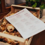 El Caminito menu resting on a crate of wild mushrooms beside a geranium at El Caminito Palma