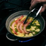 Prawns and sliced garlic sizzling in olive oil in a pan over a flame at El Caminito Palma