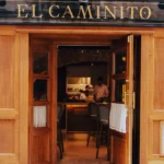 Gold El Caminito lettering above the wooden entrance doors opening to the kitchen at El Caminito Palma