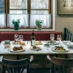 Banquette table laid with a full spread of dishes and wine by a curtained window at El Caminito Palma