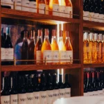 Backlit shelves lined with house El Camino and other wine bottles at El Caminito Palma