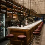 Long marble bar counter lined with burgundy stools beneath a star-panelled ceiling and wine wall at El Camino Restaurant