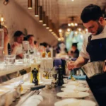 Chef plating a dish at the counter as guests look on at El Camino Restaurant