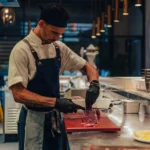Chef in a blue apron slicing beef at the counter at El Camino Restaurant