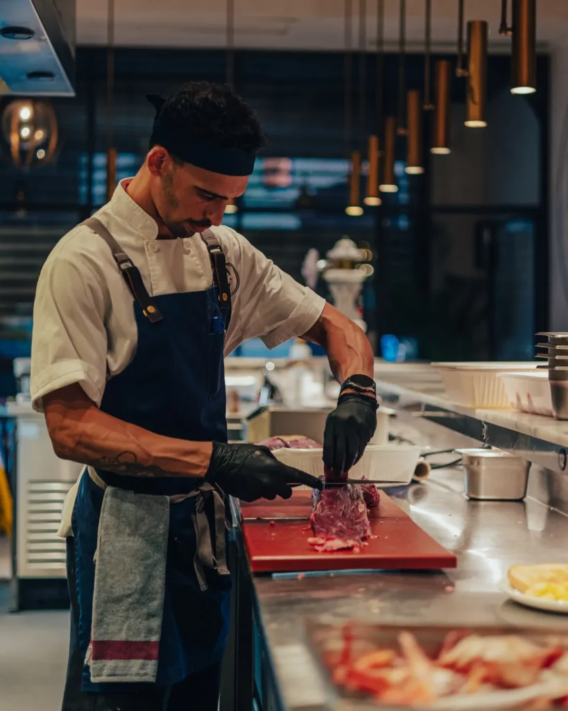 Chef in a blue apron slicing beef at the counter at El Camino Restaurant